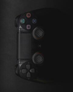 Moody close-up of a black gaming controller in low light with colorful buttons.